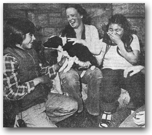 Inuit students Jacob Palliser (left) and Elizabeth Williams (right) join new friend Mary Hill, CCHS - C'80, playing with a four-legged friend. The Inuit teenagers are among a group of 13 in Montreal on an exchange program with pupils from St. Lambert. - Montreal Gazette, May 1980.